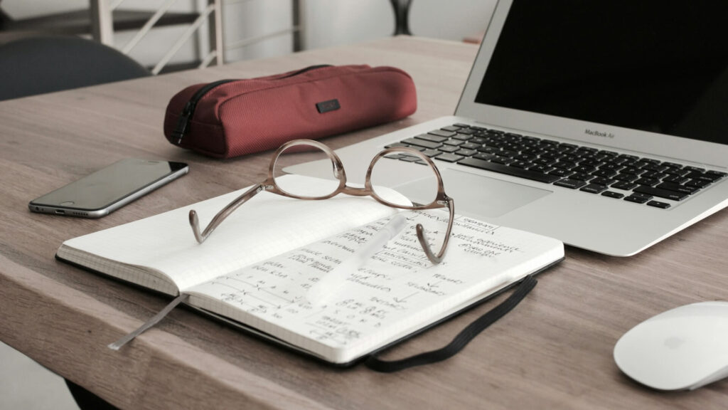 open laptop with notes and glasses
